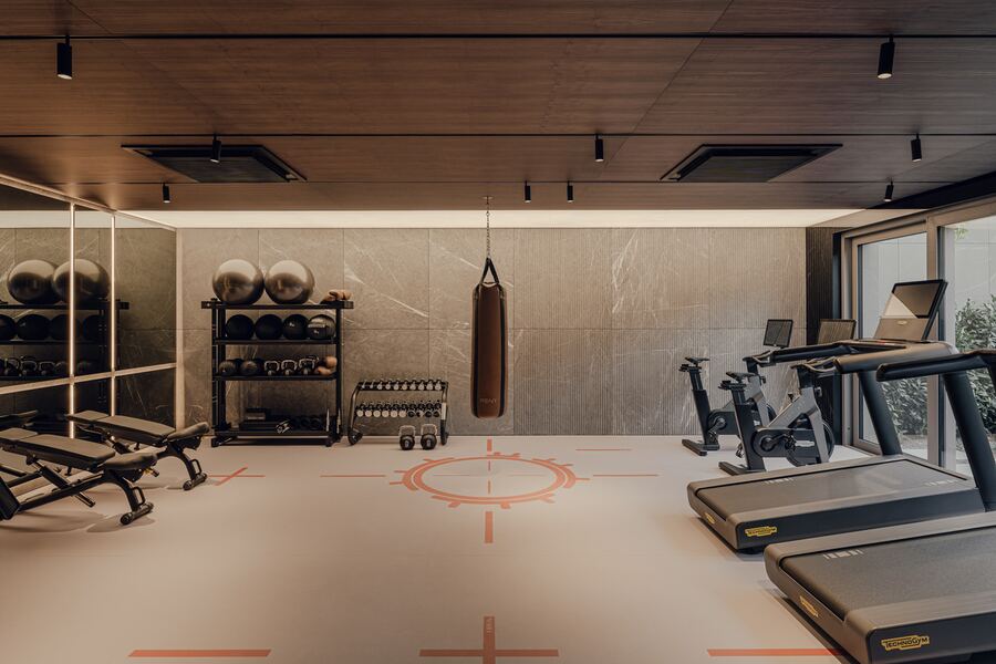 Sala fitness — bieżnie, rowery treningowe, hantle, worek treningowy i lustrzana ściana